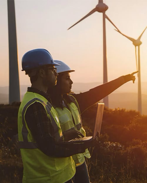 Two Engineers with security hermet in the field of wind turbines.